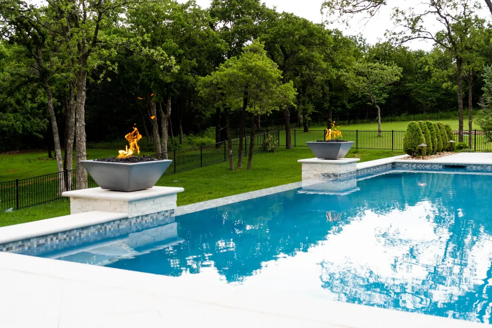 Blue swimming pool with surrounding landscaping and poolside furniture