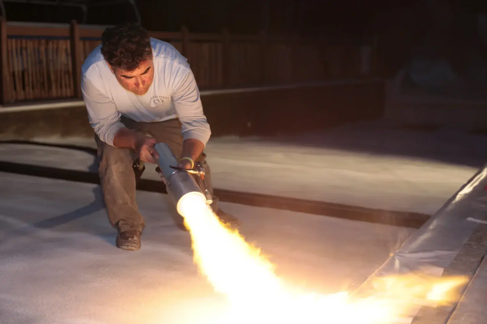Technician flame-spraying polymer coating onto a prepared surface