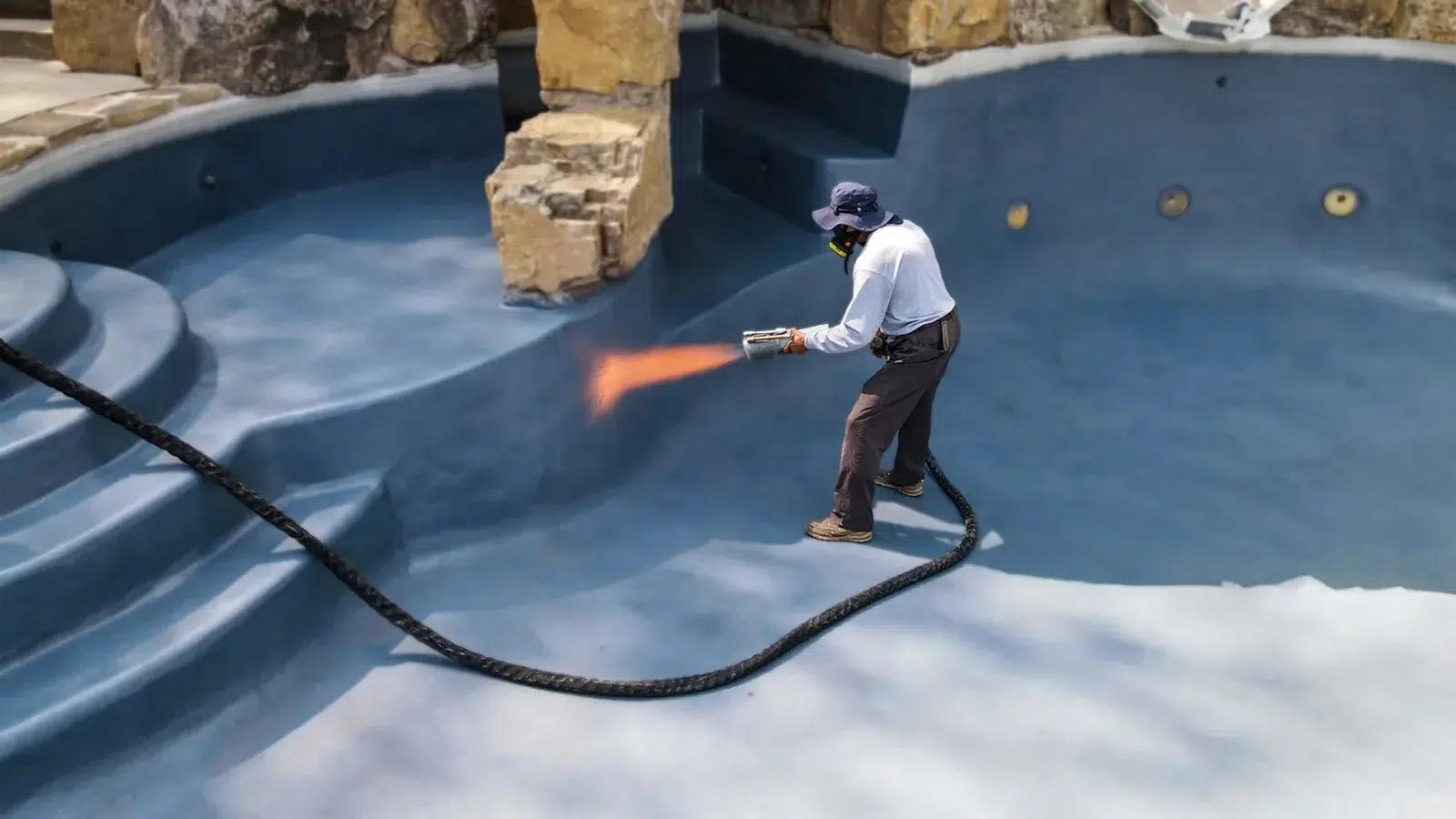 Installer applying a polymer coating inside an empty swimming pool