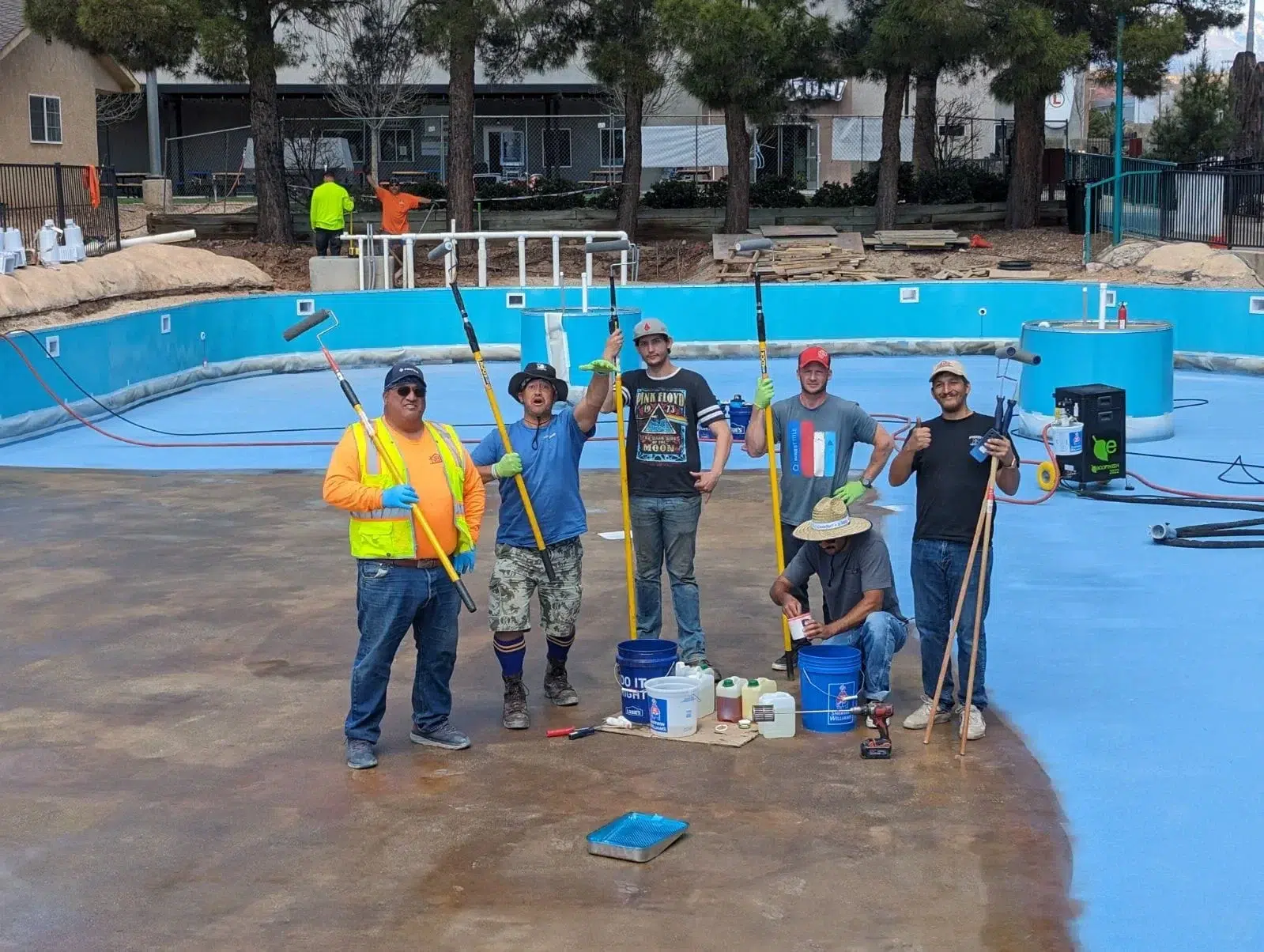 Pool coating installation team standing beside a swimming pool