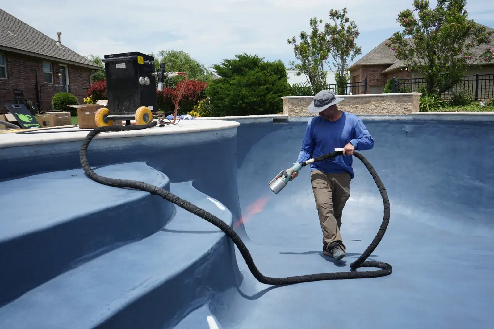 Technician applying ecoFINISH inside a drained blue swimming pool